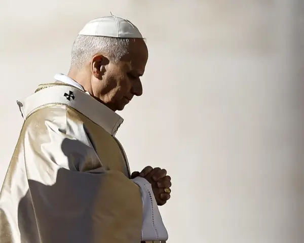 Papież w białej piusce i złotej szacie modli się, wierzę w boga. W jego oczach widać głęboką wiarę.