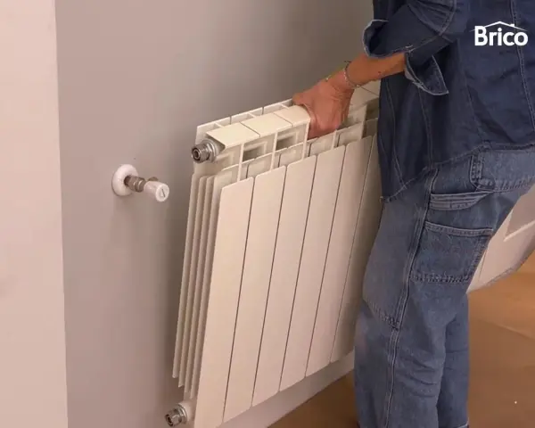 Persona quitando radiadores para pintar la pared.