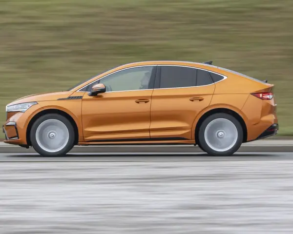 Pomarańczowy elektryczny SUV coupe w ruchu, widok z boku.
