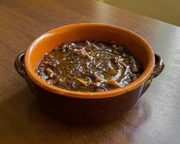 Una ciotola di terracotta con un saporito piatto di pasta e lenticchie, condito con olio d'oliva.