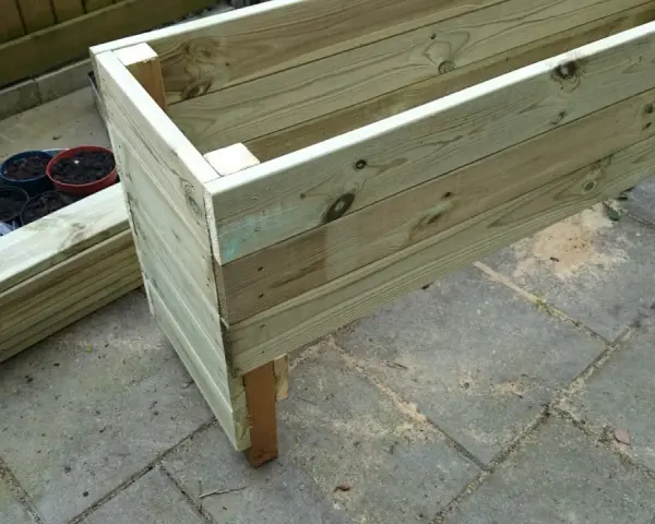 Påbörjat projekt att bygga blomlåda av tryckimpregnerat virke. Några krukor med jord står redo.