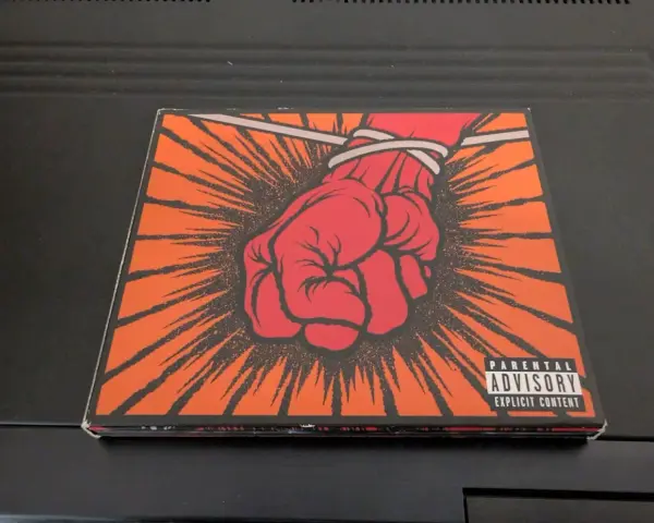 Okładka płyty Metallica "St. Anger" z czerwoną, zawiązaną pięścią i napisem "Parental Advisory".