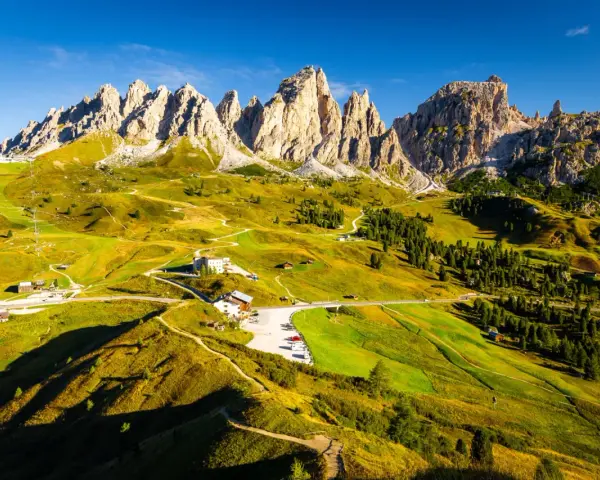 Panorami mozzafiato sull'**Alta Via numero 2 Dolomiti**. Sentieri serpeggianti tra prati verdi e imponenti vette rocciose sotto un cielo azzurro.