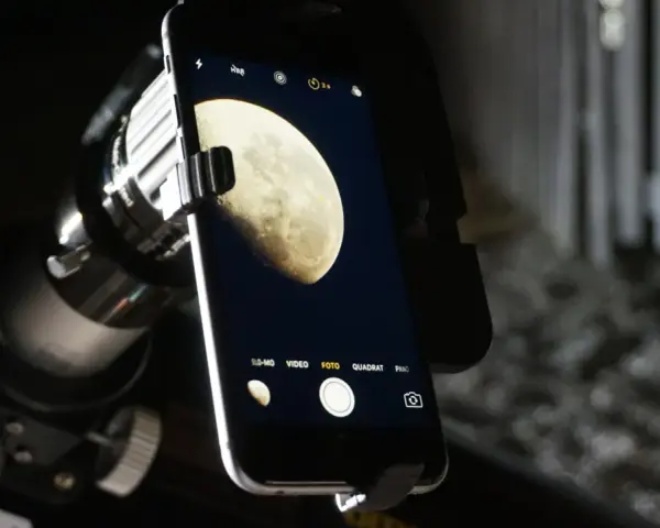 Mit dem Handy den Mond fotografieren: Ein Smartphone ist über einen Adapter an einem Teleskop befestigt, um den Mond abzulichten.