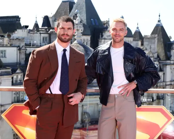 Due uomini posano con stile: uno in completo marrone, dimostrando come abbinare il marrone uomo con eleganza, l'altro con giacca di pelle e pantaloni chiari.