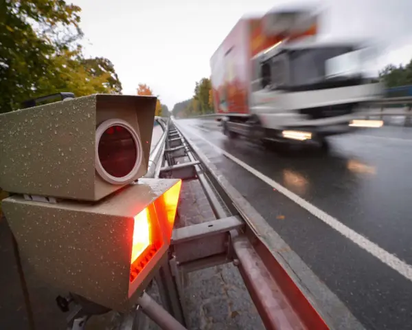 Blitzlicht erhellt die nasse Fahrbahn. Ein LKW rast vorbei. Das Zeugnisverweigerungsrecht bei Blitzern ist ein Thema für Fahrer.