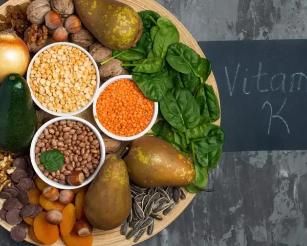 En bricka med mat rik på vitamin K1: spenat, päron, avokado, nötter, linser, bönor, torkade aprikoser, solrosfrön och choklad.