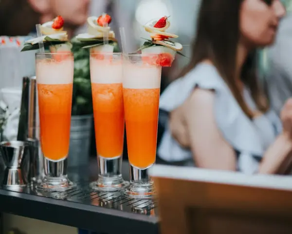 Orzeźwiający drink dla kobiet, ozdobiony owocami i listkami, gotowy do podania na letnim przyjęciu.