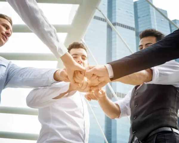 Un gruppo di uomini d'affari unisce i pugni, mostrando le loro caratteristiche personali di unità e determinazione.