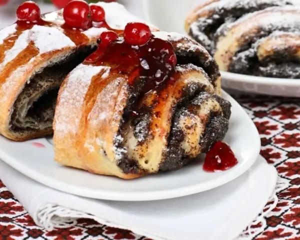 Saftige Mohnschnecken, verziert mit Kirschen und Puderzucker. Ein Genuss, der an die süßen Momente einer Schwangerschaft erinnert.
