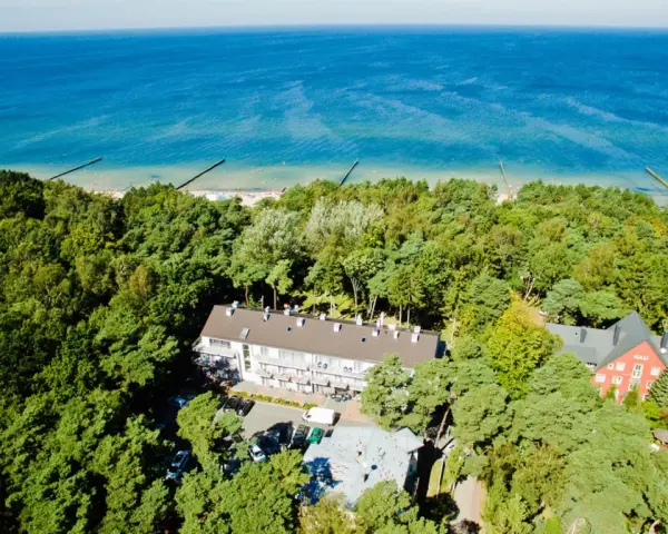 Widok z lotu ptaka na hotel otoczony lasem, z widokiem na morze. Idealne miejsce na wakacje, sprawdź nasz tui kod rabatowy!