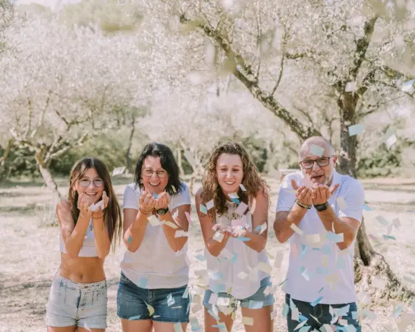 Photographie lifestyle : une famille lance des confettis sous des arbres fleuris, un moment de joie capturé.