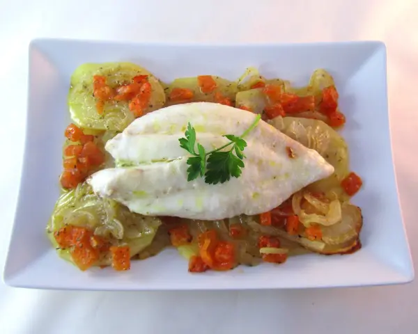 Filete de pescado blanco sobre patatas y zanahorias asadas, un delicioso gallo al horno.