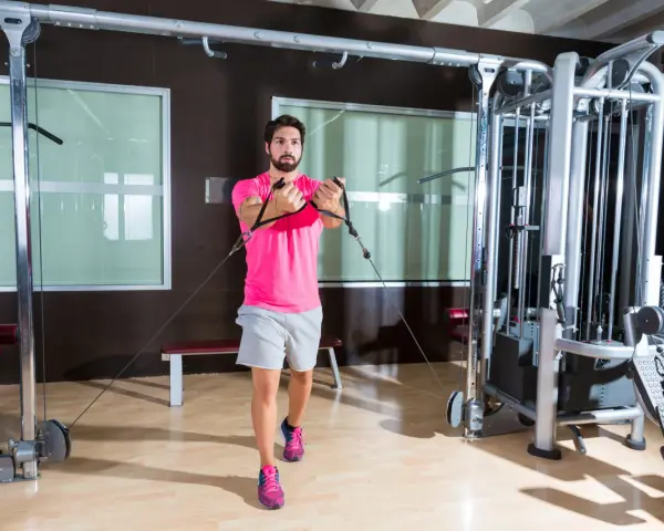 Man tränar bröstmuskler med en flyes maskin i ett modernt gym.
