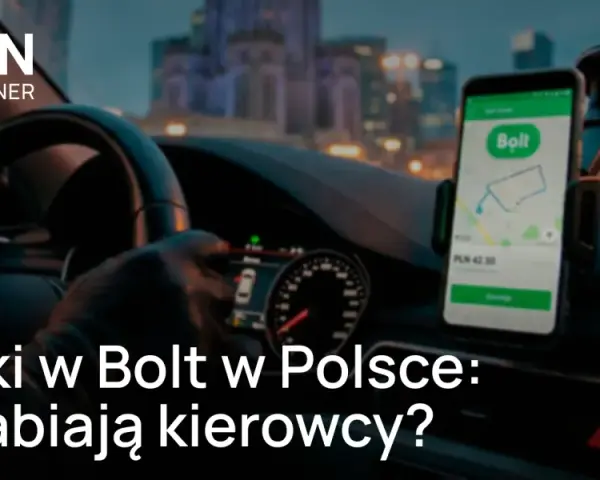 Kierowca w rękawiczkach trzyma kierownicę, na desce rozdzielczej widoczny telefon z aplikacją Bolt. Sprawdź, ile zarobisz za km w Bolt.