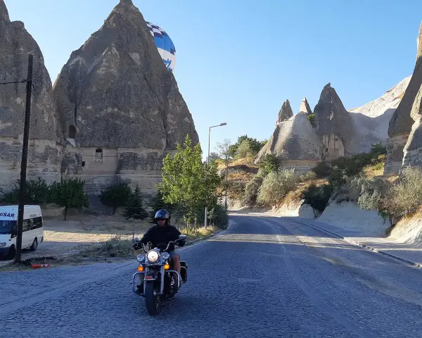 Niesamowita podróż motocyklem przez Kapadocję w Turcji. W tle widać latający balon i skalne formacje.