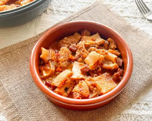 Un cuenco de barro con callos a la vizcaina, un plato tradicional español lleno de sabor y textura.