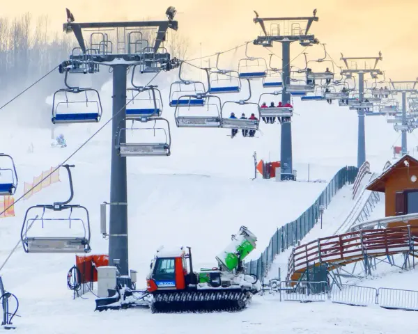 Kolejka linowa na stoku narciarskim w Bełchatowie, ratrak przygotowuje trasę.