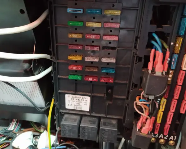 Panel bezpieczników w Mercedesie GL. Widoczne bezpieczniki i przekaźniki, a także etykieta z opisem.