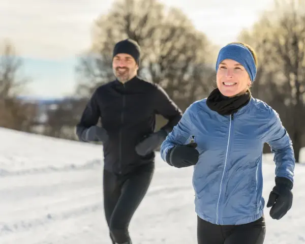 Ein Paar genießt das Laufen im Winter. Sie tragen passende Winterkleidung, um sich warm zu halten.