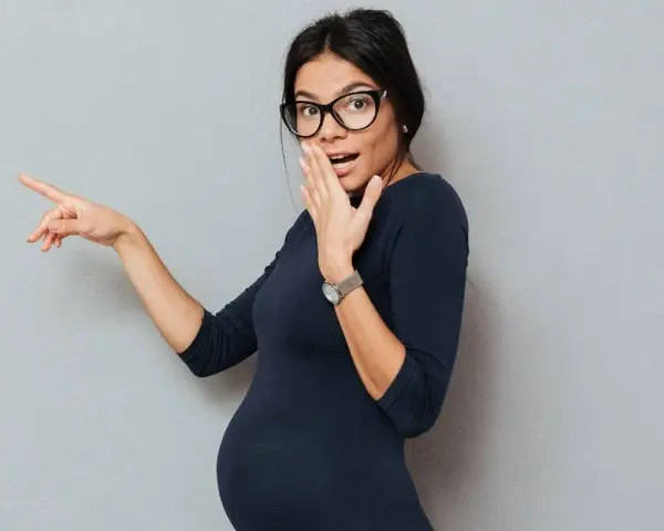 Donna incinta con occhiali indica sorpresa, forse per la secchezza in gravidanza.