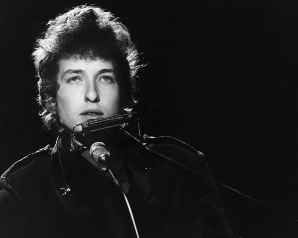 Bob Dylan spielt Mundharmonika, ein wahrer "rolling stone" auf der Bühne, mit seinem charakteristischen Blick.