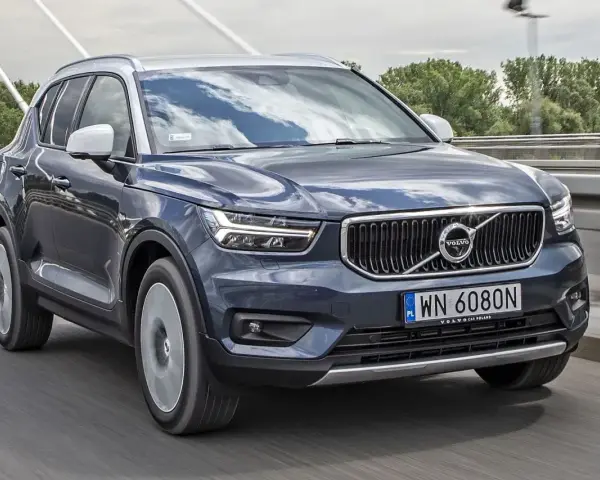 Ciemnogranatowy Volvo XC40 jedzie po moście. Sprawdź aktualną volvo xc40 cena i ofertę.
