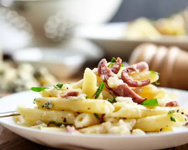 Piatto di pasta porri e salsiccia, cremoso e saporito, con pezzetti di formaggio e erbe fresche.