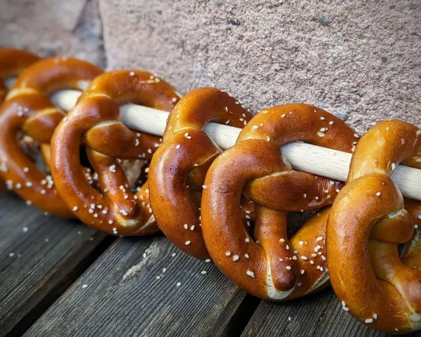 Frisch gebackene Brezeln, perfekt für ein Laugengebäck Rezept. Mit grobem Salz bestreut, liegen sie auf Holzbrettern.