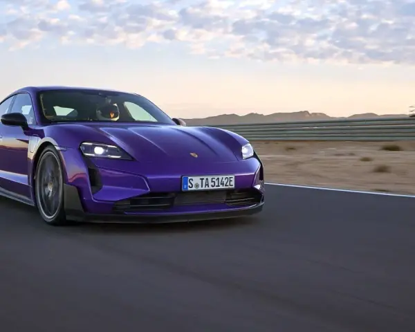Fioletowe Porsche Taycan na torze wyścigowym podczas zachodu słońca.