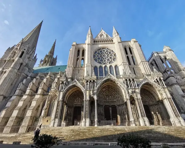 The magnificent Chartres Cathedral, with its iconic rose window and soaring spires, stands majestically against a clear blue sky.