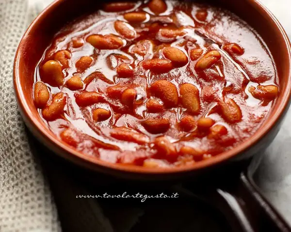 Un primo piano di fagioli all'uccelletto in una ciotola di terracotta, un classico delle ricette italiane.