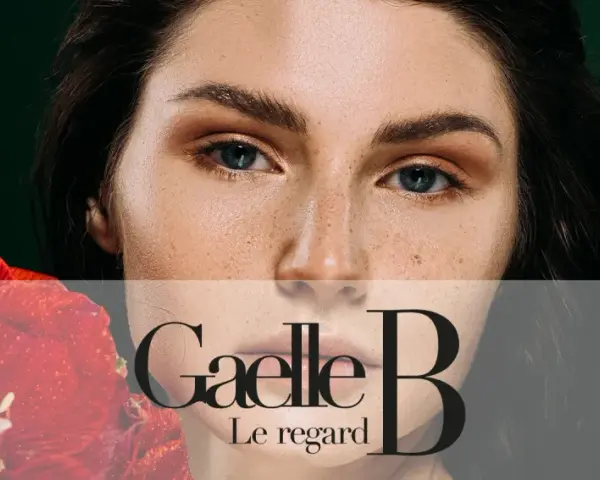 Un visage de femme avec des taches de rousseur naturelles, tenant une fleur rouge. Le regard est intense.