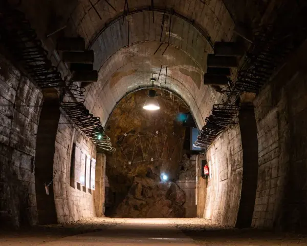Wnętrze tunelu w Górach Sowich. Betonowe ściany, łukowe sklepienie i oświetlenie tworzą mroczny klimat.
