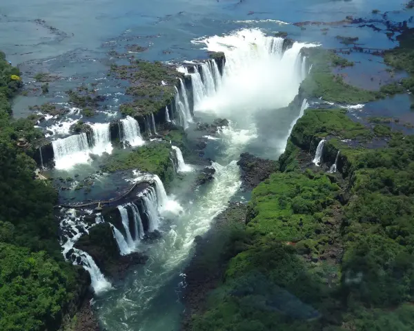 An aerial view of Iguazu Falls, a breathtaking cascade of water surrounded by lush green jungle. A perfect destination for 2 days of unforgettable adventure.