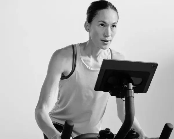 Focused woman powering through a hiit cycle workout on a stationary bike, her muscles engaged.
