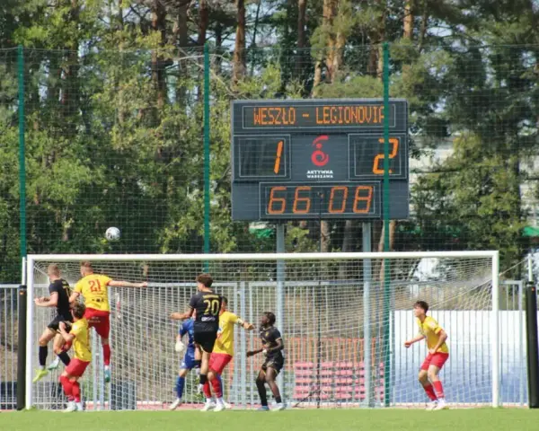 Piłkarze walczą o piłkę pod bramką. Na tablicy wyników Weszło - Legionovia 1:2. Jakub Wysocki w akcji.