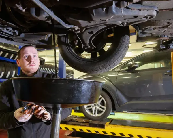 Mechanik spuszcza zużyty olej z samochodu. Zastanawiasz się, ile trwa wymiana oleju i filtrów?
