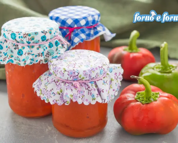 Barattoli di crema di peperoni fatti in casa, con peperoni freschi sullo sfondo.