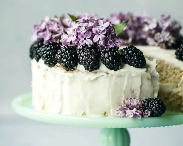 Biały tort z jeżynami i bzem, idealny przykład najmodniejszych smaków tortów.