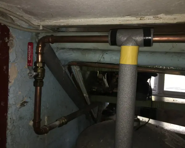 Kopparrör med isolering och en röd ventil, redo att fylla på luft i hydrofor.