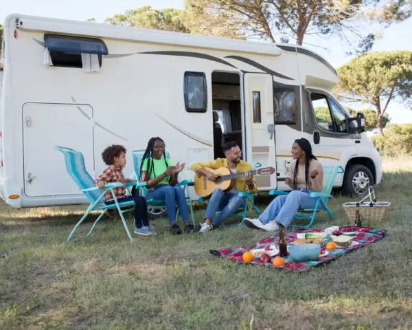 Eine Familie genießt das Camping mit Musik und Picknick vor ihrem Wohnmobil.