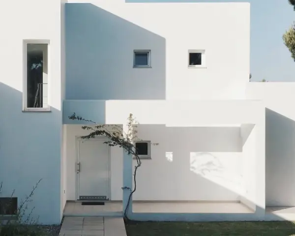 Fachada blanca moderna con sombras marcadas. La mejor pintura para fachadas exteriores protege y embellece esta arquitectura minimalista.
