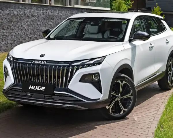 Nowy, biały chinski suv z imponującym grillem i felgami stoi na podjeździe.