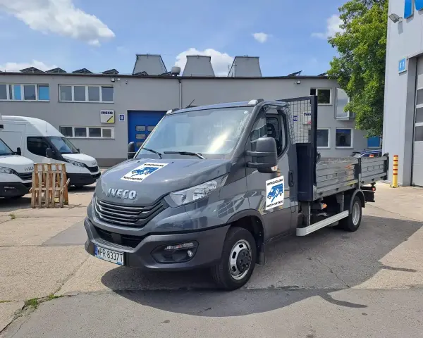 Szary Iveco z otwartą skrzynią ładunkową, idealny do wynajem wywrotki do 3,5 tony. Na drzwiach logo "Wypożyczalnia Moto-Partner".