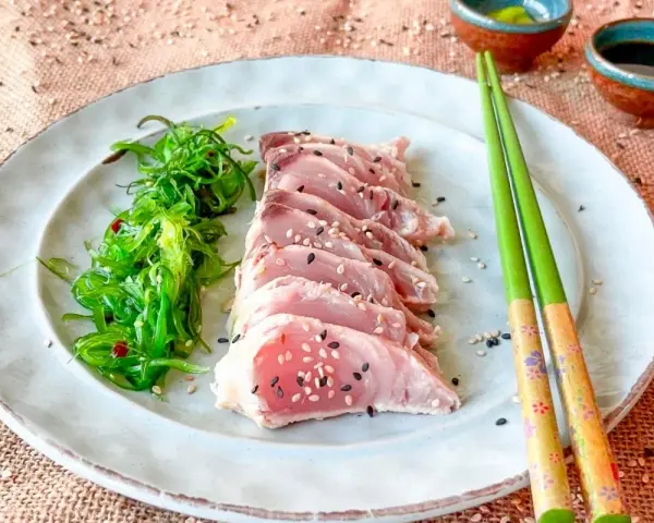 Tataki de bonito, finas lonchas de pescado crudo con semillas de sésamo, acompañadas de ensalada de algas.
