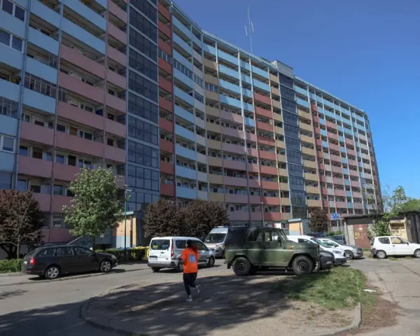 Długi, wielopiętrowy blok mieszkalny, prawdopodobnie najdłuższy blok w Polsce, z kolorowymi balkonami i oknami, na tle błękitnego nieba.
