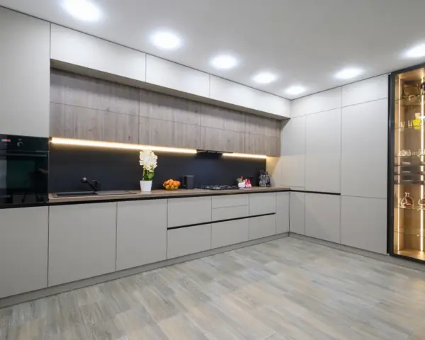 Cocina moderna con armarios grises y vitrina iluminada. El suelo de madera clara es perfecto para suelos para cocinas sin obras, aportando calidez y estilo.