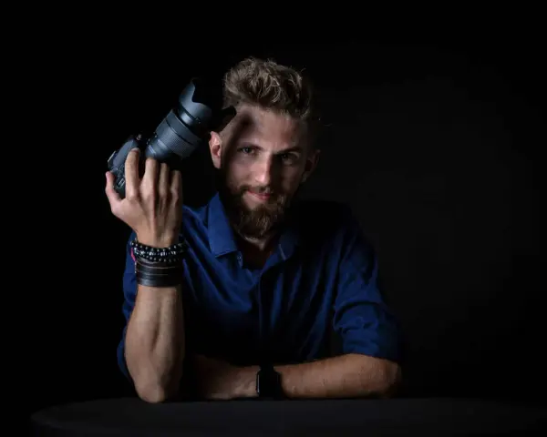 Mężczyzna z aparatem fotograficznym, gotowy do rozpoczęcia kursu fotografii.