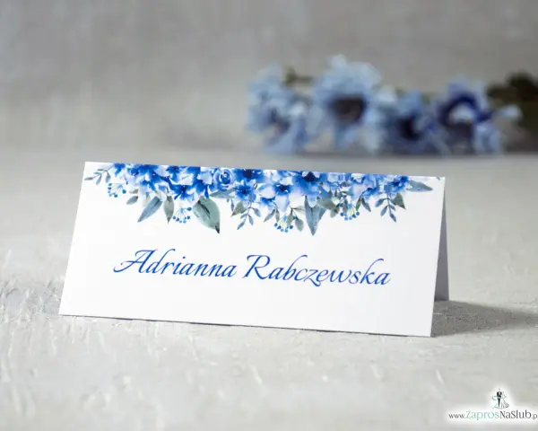 Eleganckie winietki dla usługodawców z motywem niebieskich kwiatów. Na białej kartce widnieje imię i nazwisko "Adrianna Rabczewska".